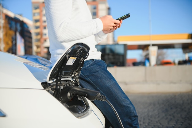 L'homme charge une voiture électrique à la station de charge