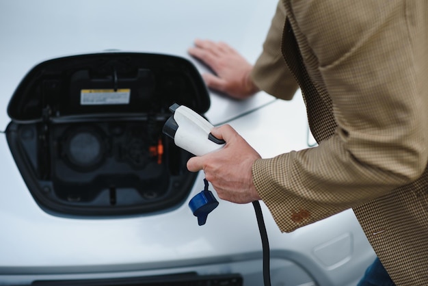 L'homme charge une voiture électrique à la station de charge