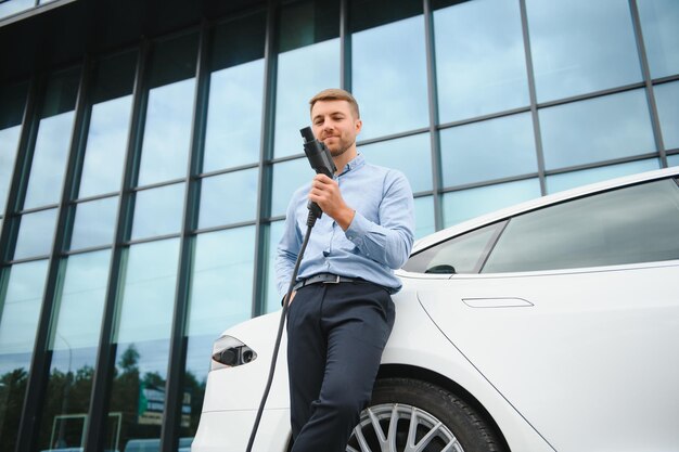 L'homme charge une voiture électrique à la station de charge