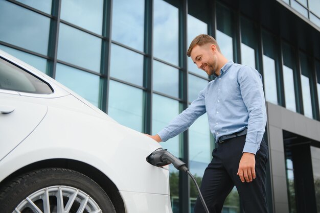 L'homme charge une voiture électrique à la station de charge