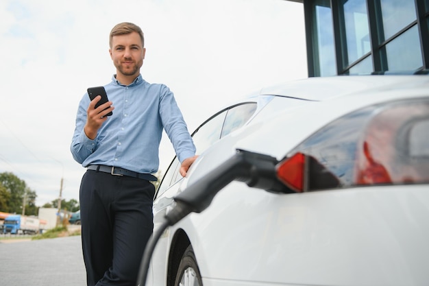 L'homme charge une voiture électrique à la station de charge