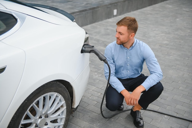 L'homme charge une voiture électrique à la station de charge