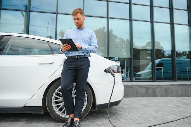 L'homme charge une voiture électrique à la station de charge