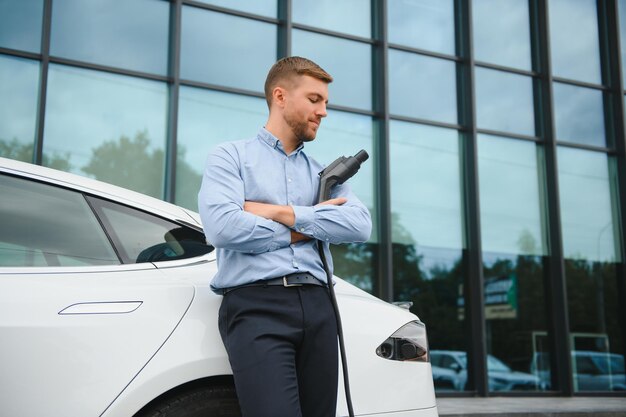 Un homme charge une voiture électrique