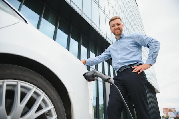 Un homme charge une voiture électrique