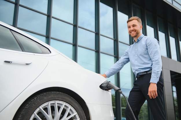 Un homme charge une voiture électrique