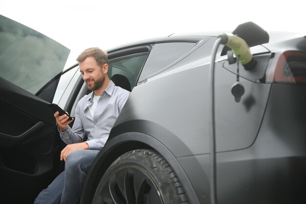 un homme charge une voiture électrique