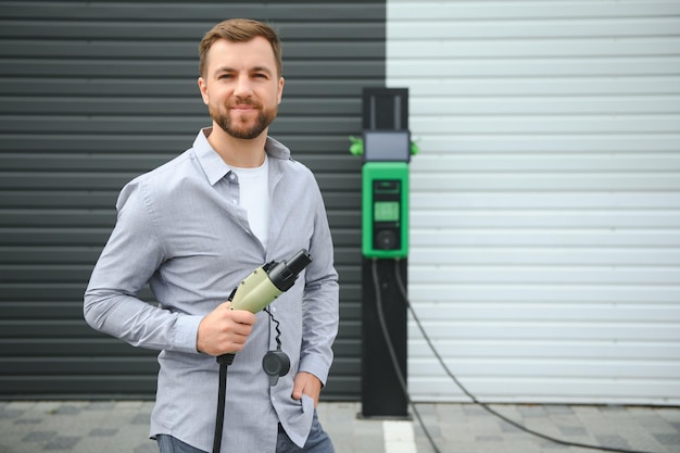 un homme charge une voiture électrique