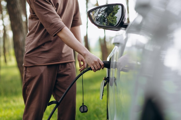 Homme chargeant une voiture électrique près de la maison