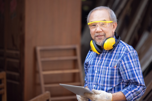 Homme charpentier dans un atelier de construction, à l'aide d'une tablette numérique