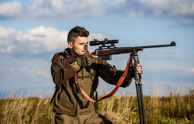 Un homme en chasse tient une arme à feu et vise sa proie.