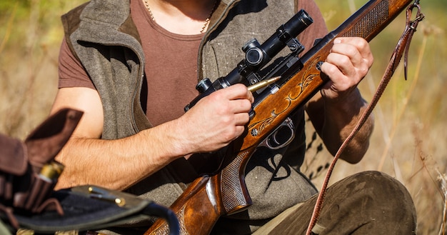 Homme chasseur. Période de chasse. Homme avec une arme à feu, un fusil. L'homme charge un fusil de chasse. Fermer. Processus de chasse pendant la saison de chasse. Chasseur mâle prêt à chasser. L'homme est à la chasse, sport.