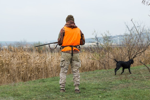 Homme chasseur en tenue de camouflage avec une arme à feu pendant la chasse à la recherche d'oiseaux sauvages ou de gibier. Saison de chasse d'automne.