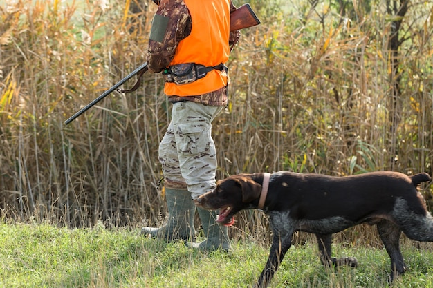 Homme chasseur en tenue de camouflage avec une arme à feu pendant la chasse à la recherche d'oiseaux sauvages ou de gibier. Saison de chasse d'automne.