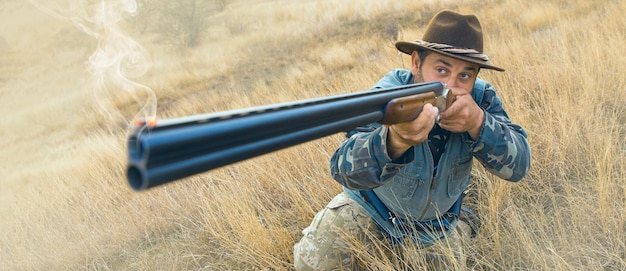 Photo homme chasseur en tenue de camouflage avec une arme à feu pendant la chasse à la recherche d'oiseaux sauvages ou de gibier