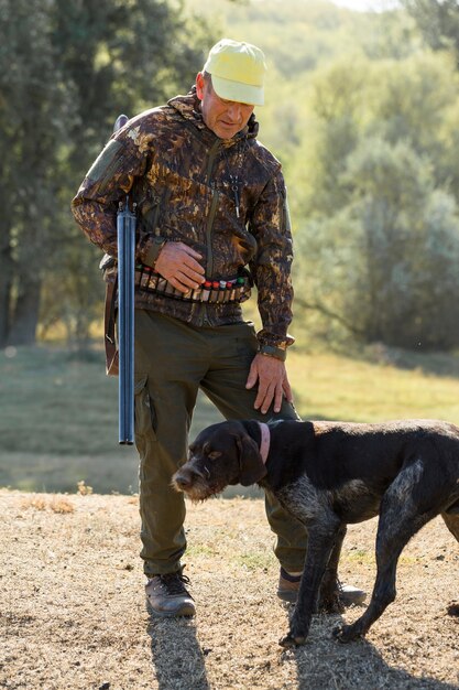 Homme chasseur en tenue de camouflage avec une arme à feu pendant la chasse à la recherche d'oiseaux sauvages ou de gibier