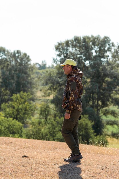 Homme chasseur en tenue de camouflage avec une arme à feu pendant la chasse à la recherche d'oiseaux sauvages ou de gibier.