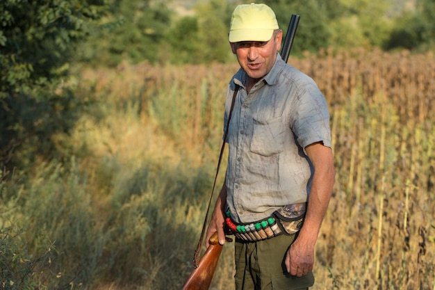 Homme chasseur en tenue de camouflage avec une arme à feu pendant la chasse à la recherche d'oiseaux sauvages ou de gibier.