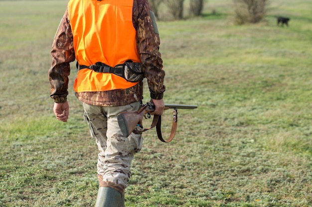 Homme chasseur en tenue de camouflage avec une arme à feu pendant la chasse à la recherche d'oiseaux sauvages ou de gibier