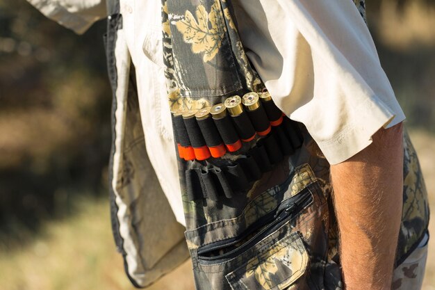 Homme chasseur en tenue de camouflage avec une arme à feu pendant la chasse à la recherche d'oiseaux sauvages ou de gibier