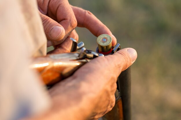 Homme chasseur en tenue de camouflage avec une arme à feu pendant la chasse à la recherche d'oiseaux sauvages