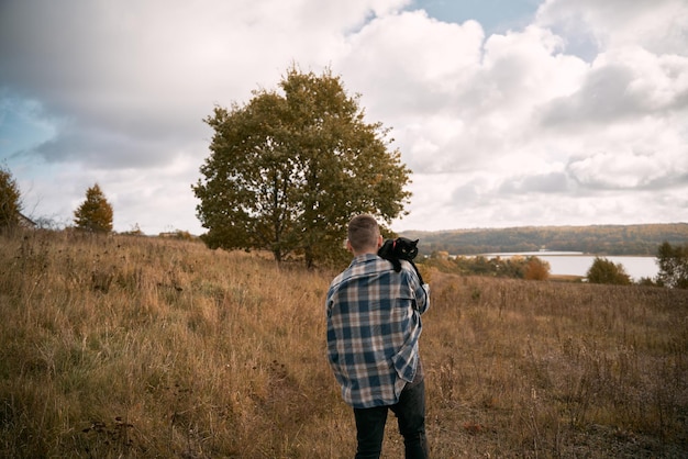 Homme avec un chat noir sur son épaule Homme barbu portant une chemise à carreaux en plein air avec son animal domestique préféré