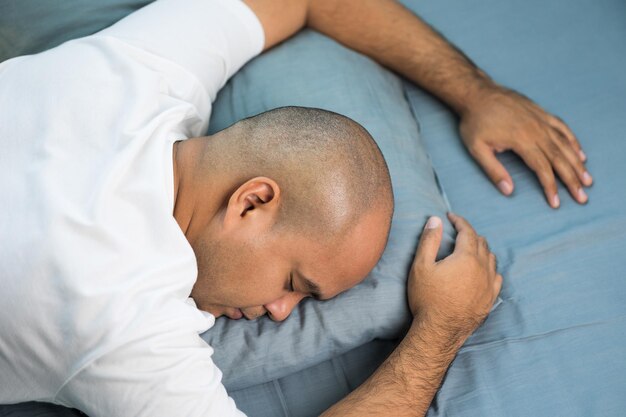 Un homme chauve asiatique d'environ 30 ans en t-shirt blanc dort