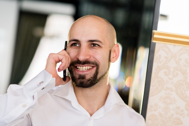 Un homme chauve brutal parlant au téléphone.