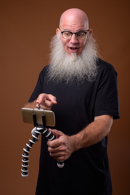 Homme chauve mature avec une longue barbe grise sur brun