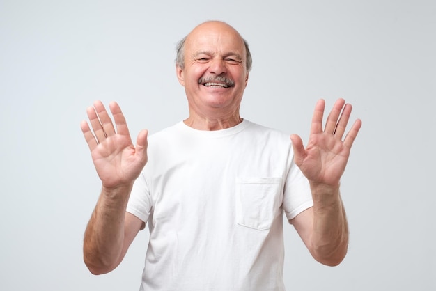 Homme chauve montre dix doigts et rit joyeusement isolé sur fond blanc