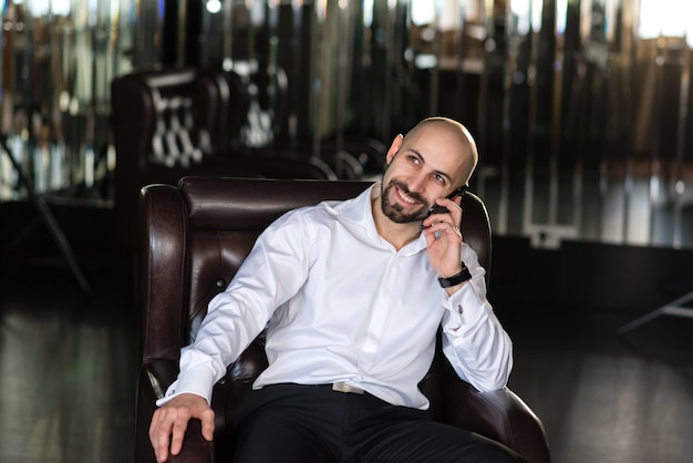 Un homme chauve parle au téléphone.