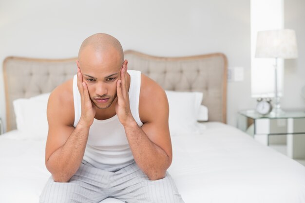 Homme chauve pensif assis sur le lit