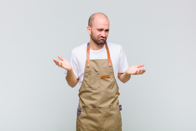 Homme chauve à la perplexité, confus et stressé, se demandant entre les différentes options, se sentant incertain