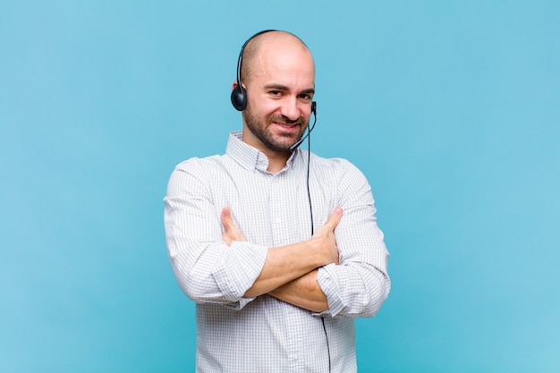 Homme chauve riant joyeusement les bras croisés, avec une pose détendue, positive et satisfaite