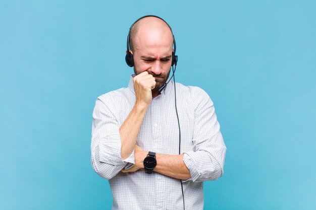 Homme chauve se sentant sérieux, attentionné et concerné, regardant de côté avec la main appuyée contre le menton