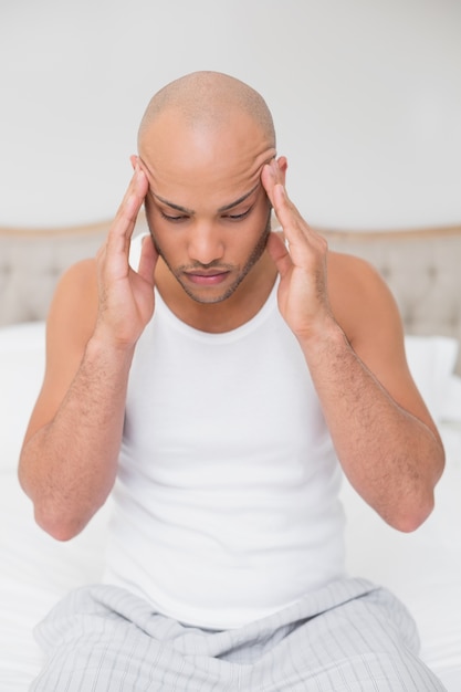 Homme chauve souffrant de maux de tête au lit