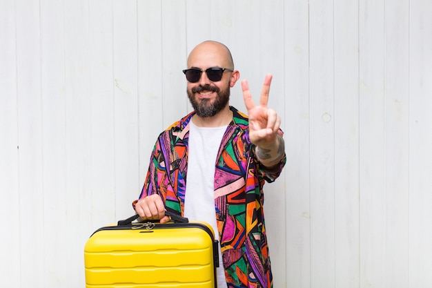 Homme chauve souriant et à la recherche de bonheur, insouciant et positif, gesticulant la victoire ou la paix d'une seule main