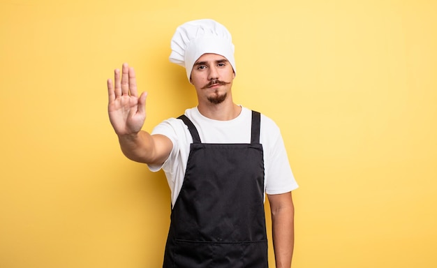 Homme de chef à la sérieuse montrant la paume ouverte faisant le geste d'arrêt