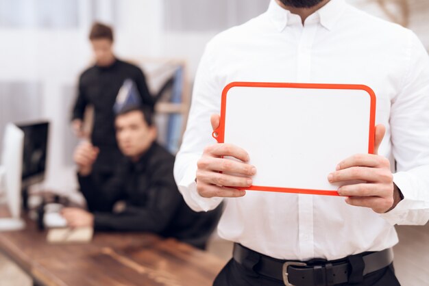 Un homme en chemise blanche est debout avec un tableau blanc.