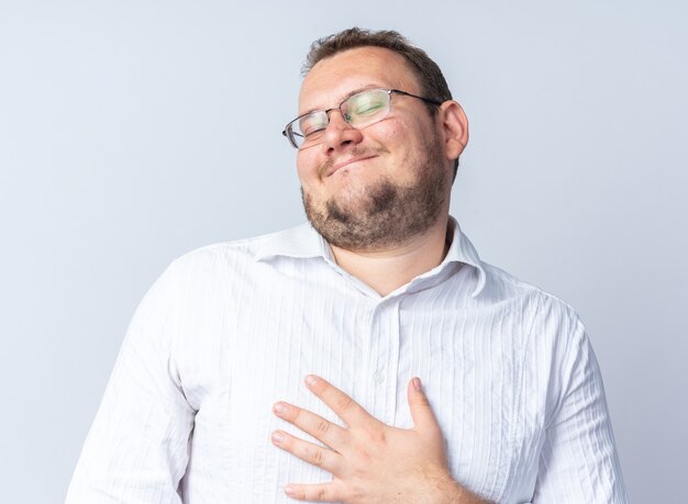 Homme en chemise blanche portant des lunettes heureux et heureux de se pointer en souriant