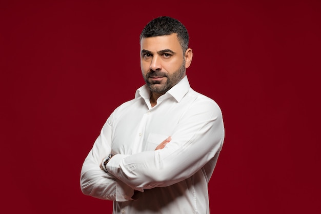 homme en chemise blanche posant en studio sur fond rouge