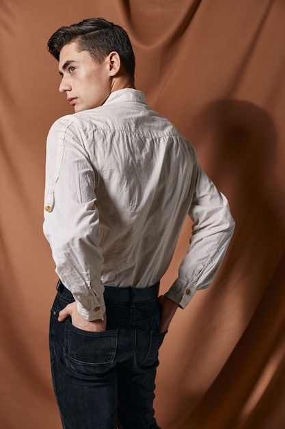 Un homme en chemise blanche se tient avec son dos en vêtements décontractés Arrière-plan en tissu de studio Photo de haute qualité