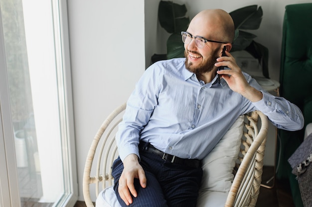 Homme en chemise bleue avec une barbe, parler au téléphone et rire