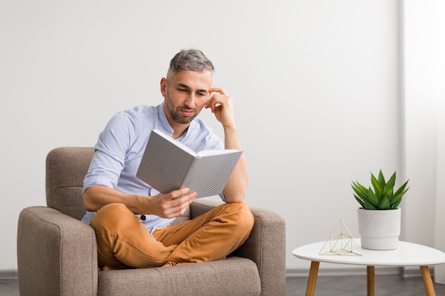 Homme en chemise bleue lit dans un livre