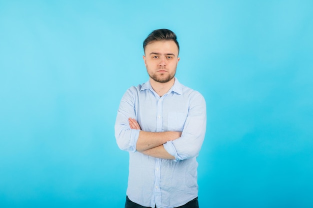 homme en chemise bleue avec les mains jointes se dresse sur fond bleu