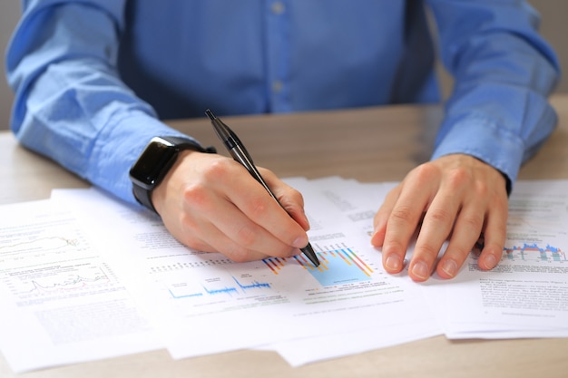 Homme en chemise bleue avec une montre intelligente noire montrant sur le rapport annuel