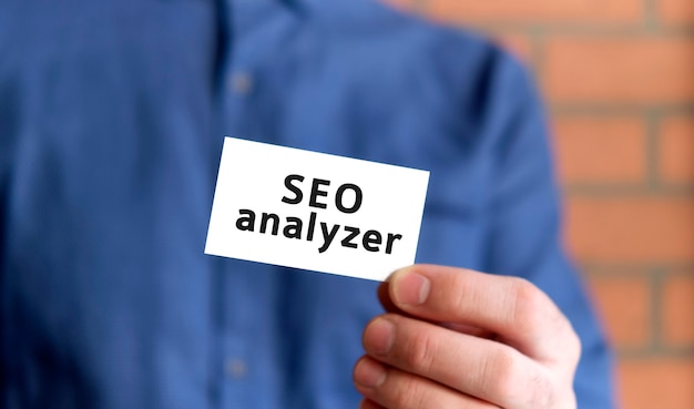 Un homme en chemise bleue tient une pancarte avec le texte de l'audit SEO n d'une part