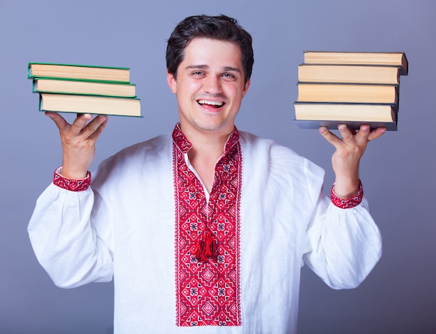 Homme en chemise de broderie avec des livres.