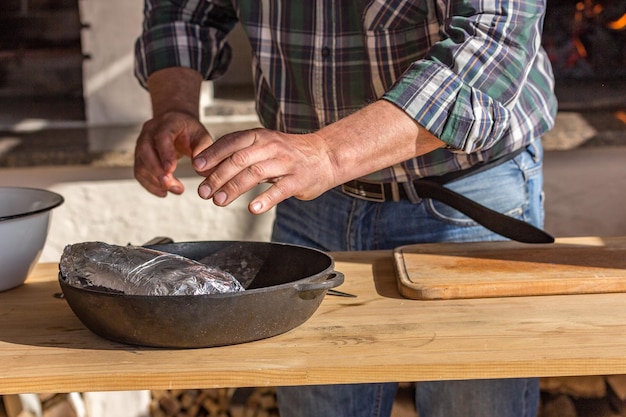 Photo un homme en chemise à carreaux cuisine du porc dans les coulisses de la cuisson de plats européens traditionnels au feu dans le four le concept du processus de cuisson recette chaude mouvement gelé