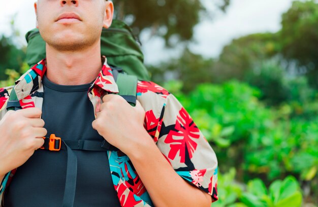 Homme avec chemise à fleurs et sac à dos